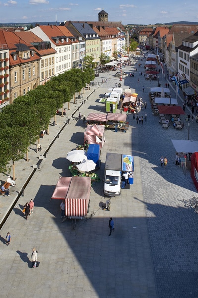 Blick von oben auf den Marktplatz mit Wasserlauf und Baumschirm