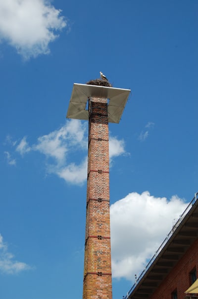 Schornstein, auf dem oben ein Storchennest thront