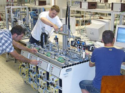 Drei Männer arbeiten gemeinsam am einer Maschine