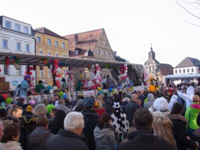 Eine dicht gedrängte Menschenmenge verfolgt den Faschingsumzug durch die Fußgängerzone.