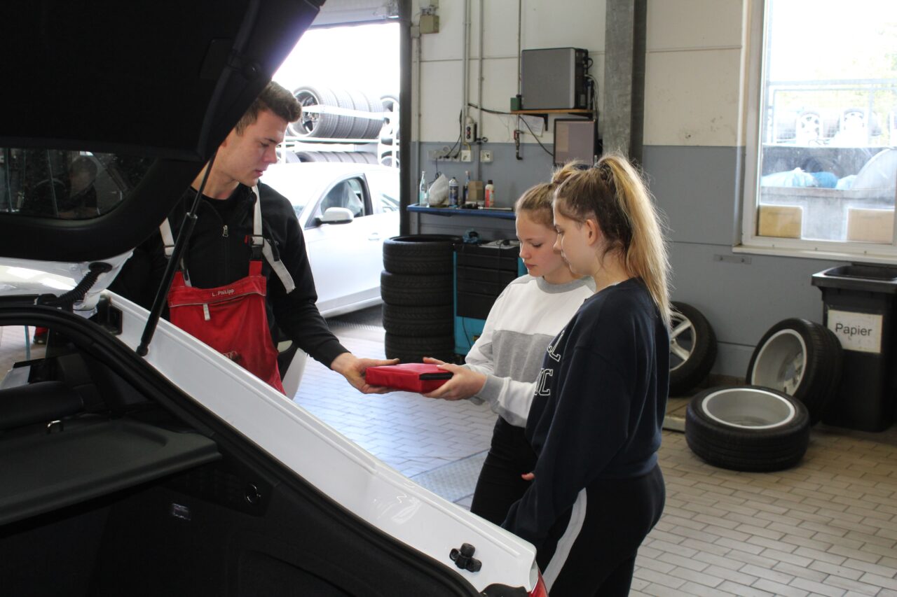 2 Mädchen beim Girls Day mit einem Mitarbeiter in der Werkstatt von Motor Nützel