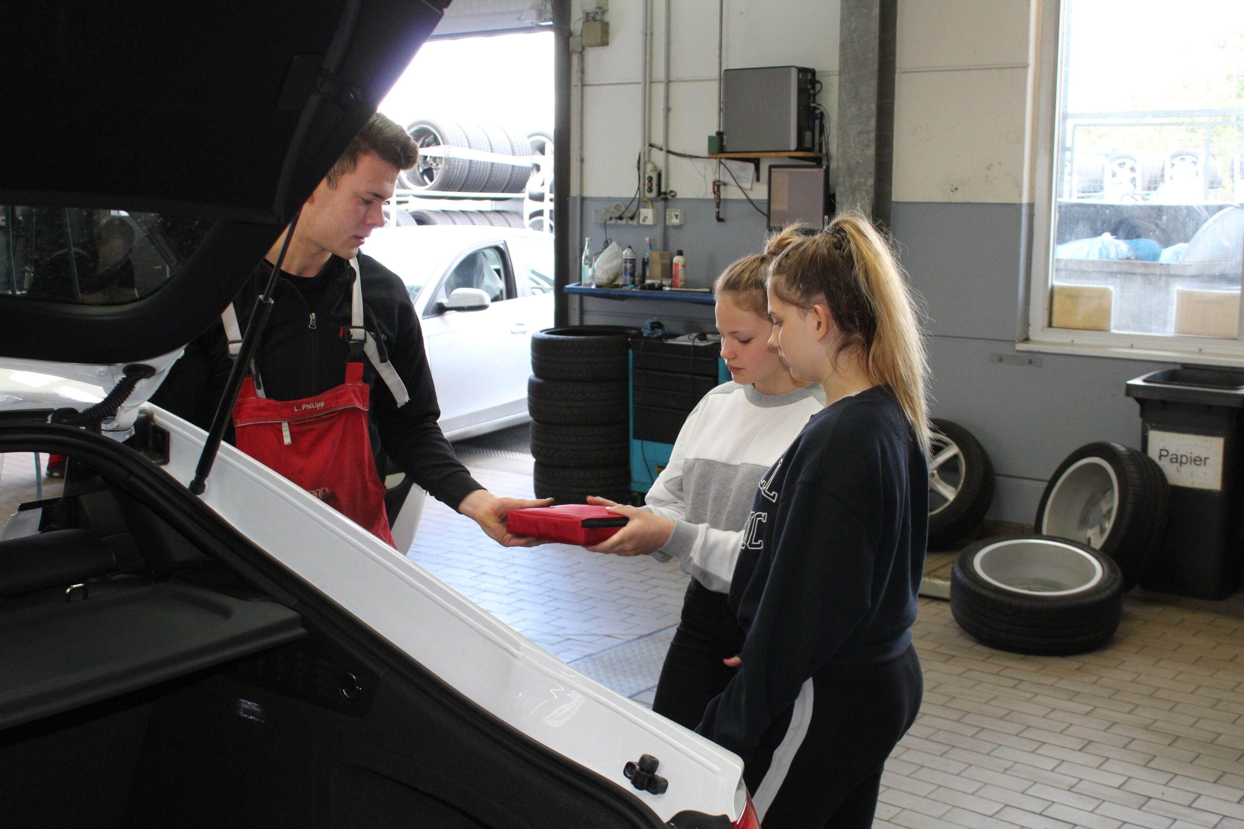 2 Mädchen beim Girls Day mit einem Mitarbeiter in der Werkstatt von Motor Nützel