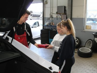 2 Mädchen beim Girls Day mit einem Mitarbeiter in der Werkstatt von Motor Nützel