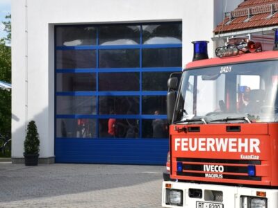 Ein Feuerwehrauto steht vor einem blauen Rolltor.