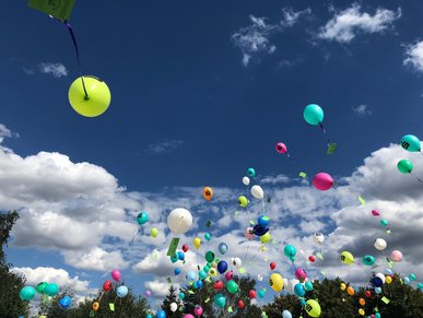 Bunte Luftballons steigen in den blauen Himmel.