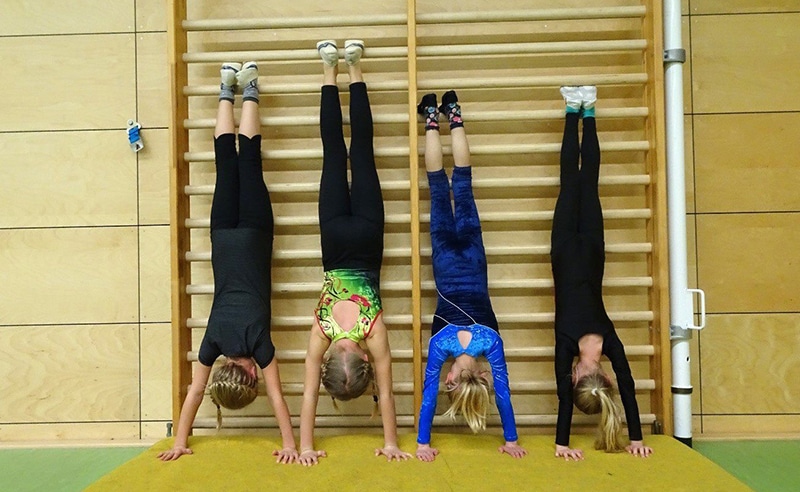 Vier Kinder üben den Handstand.