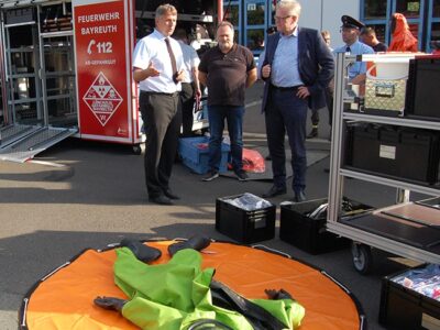 Stadtbrandrat Ralph Herrmann (links) erklärt Oberbürgermeister Thomas Ebersberger (rechts) und Stadtrat und Feuerwehrpfleger Thomas Bauske den Inhalt des neuen Abrollbehälters Gefahrengut.