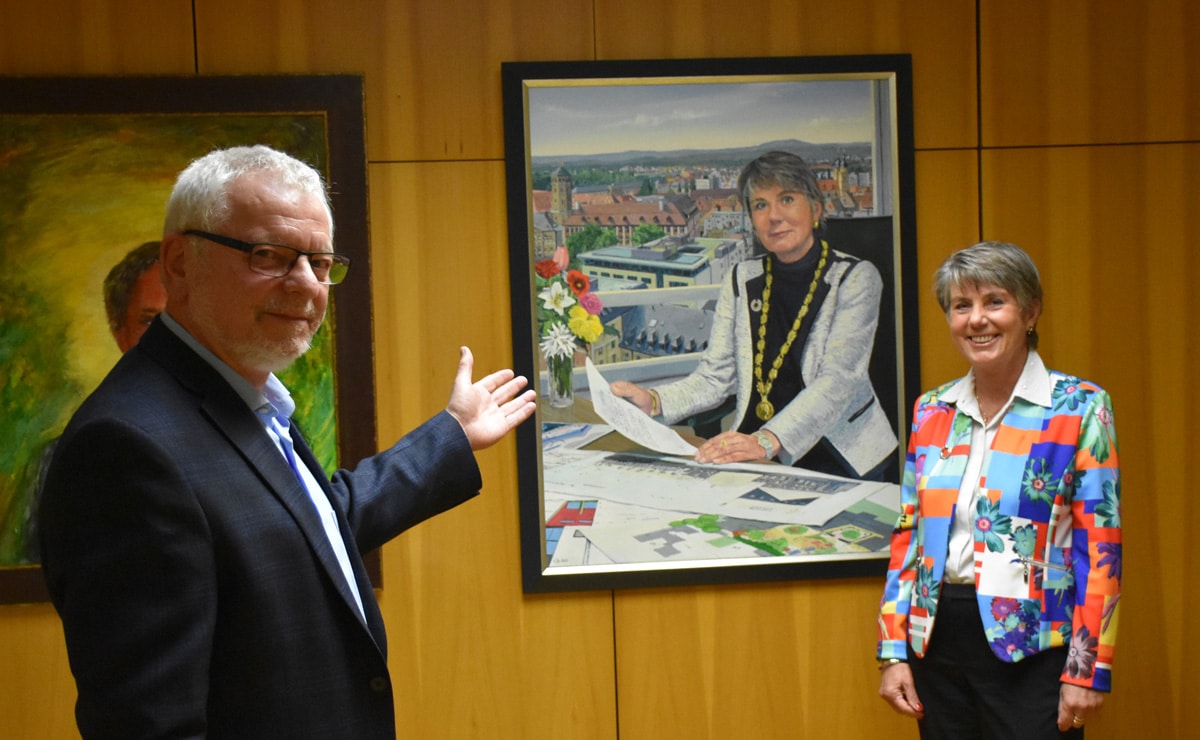 H.D. Tylle und Brigitte Merk-Erbe vor dem Portrait der ehemaligen Oberbürgereisterin.