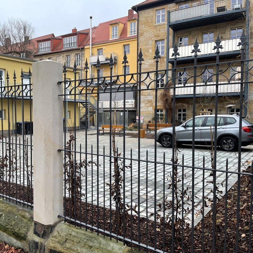 Blick durch einen Eisenzaun auf den Pocket-Park an der Dammallee