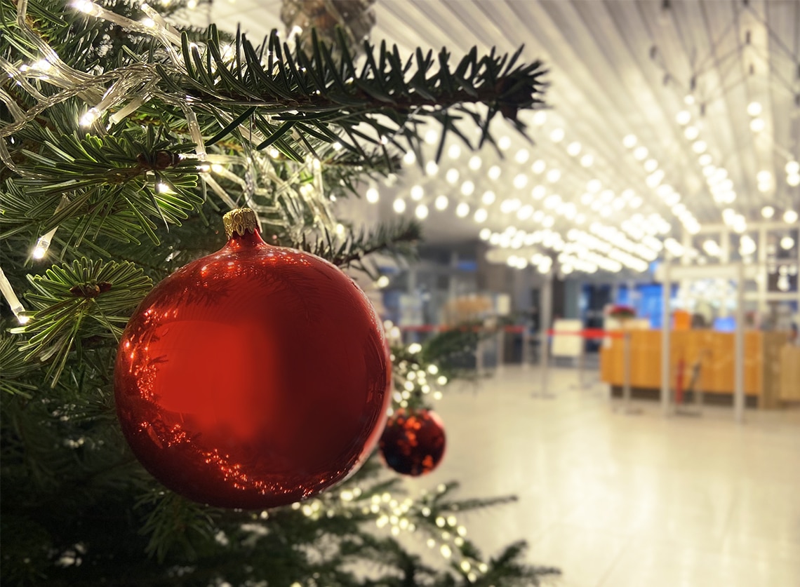 Eine rote Christbaumkugel hängt am Ast eines Weihnachtsbaums.