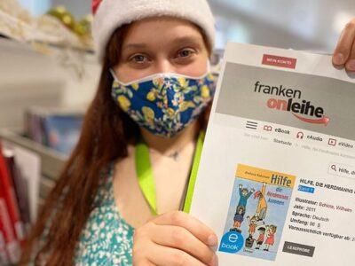 Junge Frau mit Nikolausmütze hält Zettel hoch