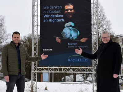 Dominik Herrmann (Siemens) und Oberbürgermeister Ebersberger vor einer Plakatwand der Kampagne "Bayreuth. Bühne für Wirtschaft".