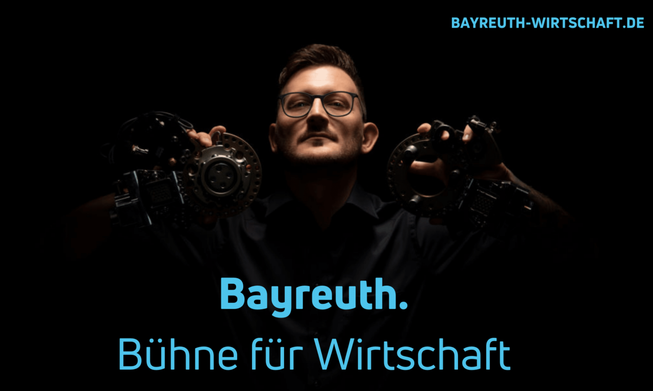 Ein junger Mann hält zwei Eisen-Formteile hoch. Darunter der Text: Bayreuth. Bühne für Wirtschaft