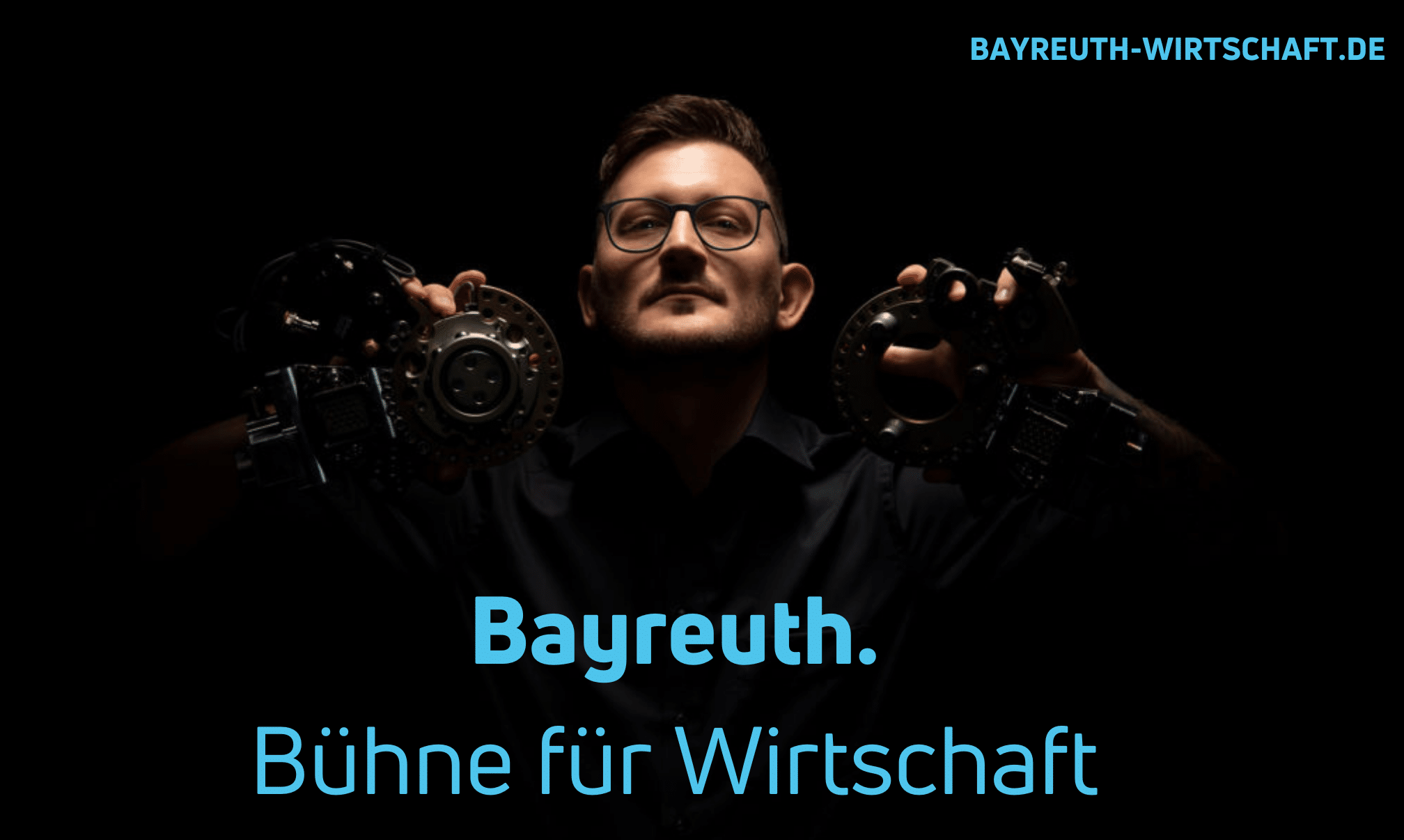 Ein junger Mann hält zwei Eisen-Formteile hoch. Darunter der Text: Bayreuth. Bühne für Wirtschaft