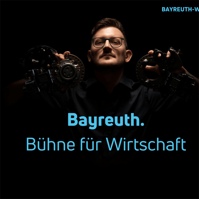Ein junger Mann hält zwei Eisen-Formteile hoch.