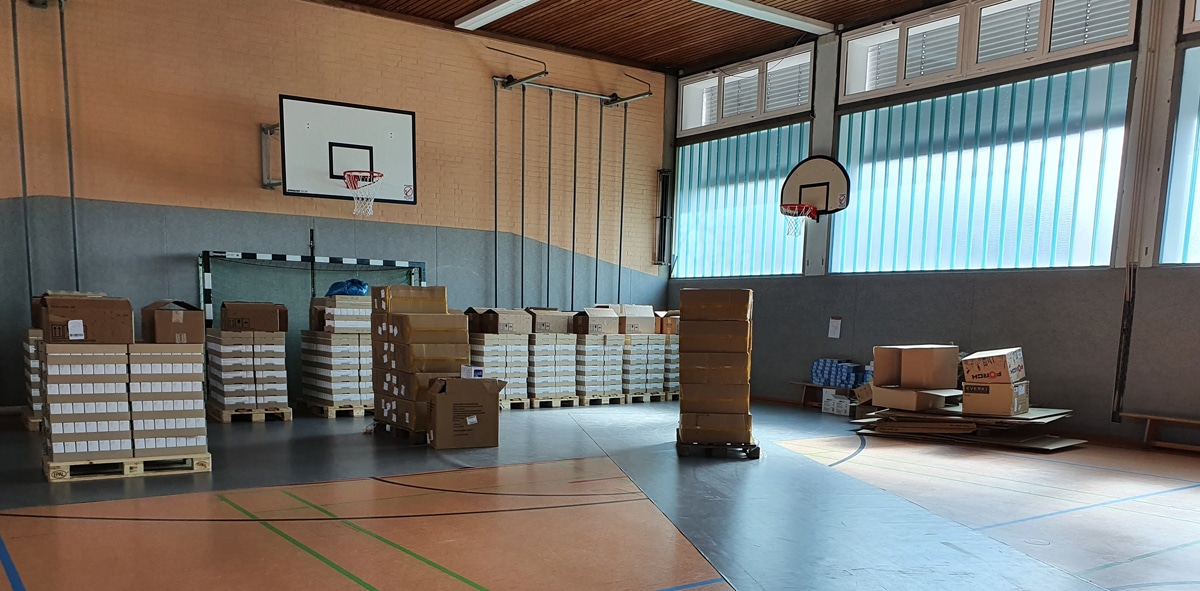 Paletten mit Selbsttests in einer Schulturnhalle.