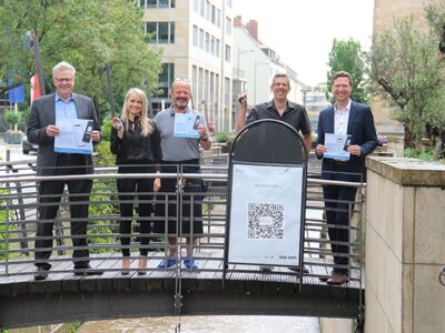 ): Oberbürgermeister Thomas Ebersberger, Jana-Lisa Mönch (Wirtschaftsförderung Landkreis Bayreuth), DEHOGA-Kreisvorsitzender Engin Gülyaprak, Matthias Mörk (Wirtschaftsförderung Stadt Bayreuth) und Landrat Florian Wiedemann zeigen Schlüsselanhänger und Aufkleber.