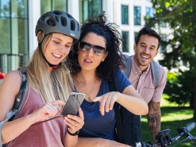 Zwei junge Frauen mit Fahrrad schauen auf ein Handy.