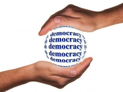 zwei Hände halten eine Kugel, auf der democracy steht
