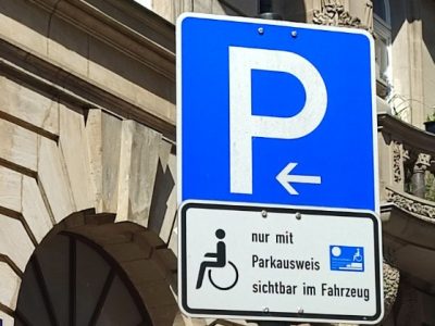 Verkehrszeichen 314 (P auf blauen Grund) mit Zusatzschild: Rollstuhlsymbol, mit Text: nur mit Parkausweis sichtbar im Fahrzeug.