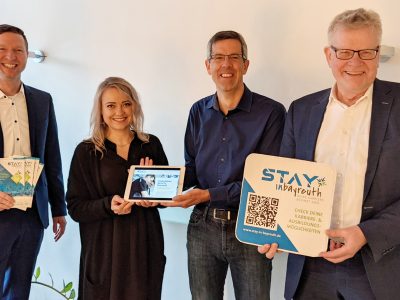 Landrat Wiedemann, OB Ebersberger und zwei Mitarbeiter präsentieren Werbematerialien für die Plattform "Stay in Bayreuth".