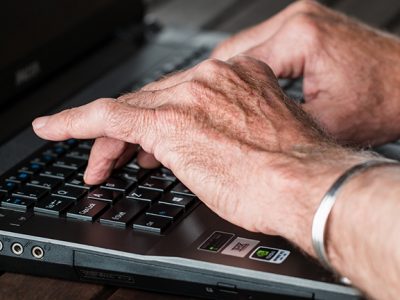 zwei Hände tippen auf der Tastatur eines Laptops