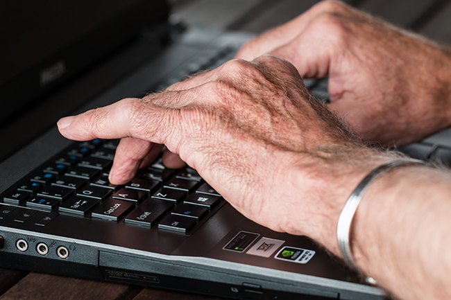 zwei Hände tippen auf der Tastatur eines Laptops