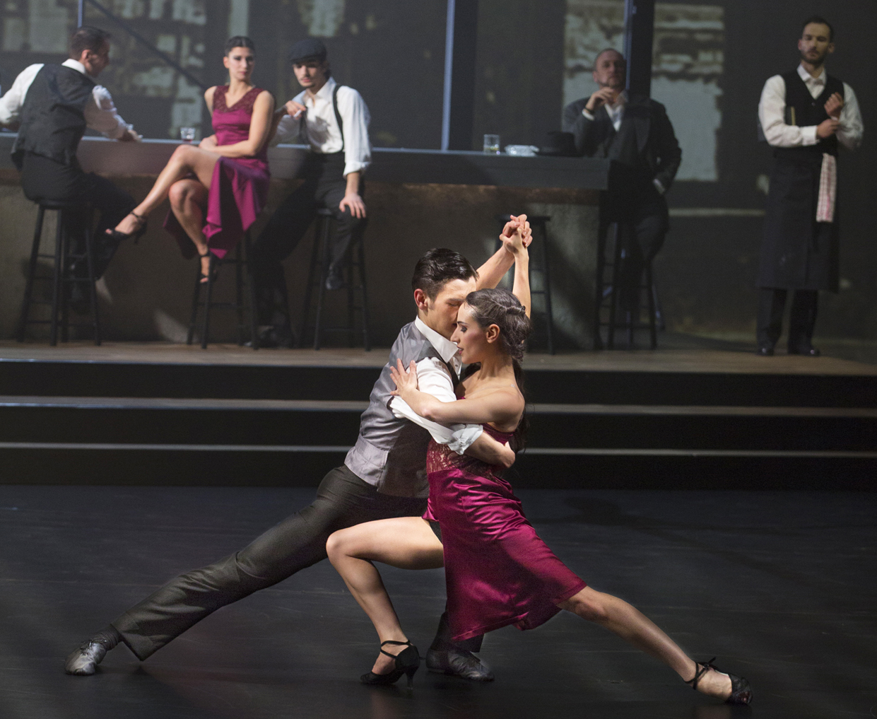 Ein Tango-Tanzpaar mit Zuschauern im Hintergrund.