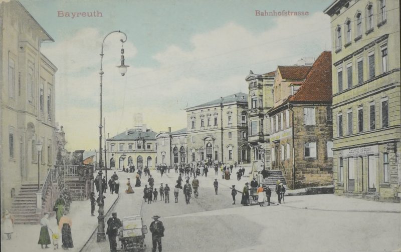 Historische Postkarte mit Blick von der Bahnhofstraße hinauf zum Bahnhofsplatz, auf der linken Seite mit dem Treppenaufgang das Wohnhaus Feustel (Bahnhofstraße 15), auf der rechten Seite Eckhaus mit Erkervorbau Bankgeschäft (Bahnhofstraße 12) (Postkarte Verlag Metz, Tübingen, 1907)