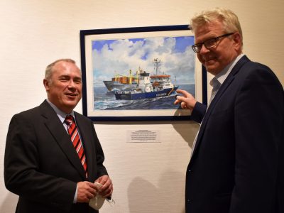 Olaf Rahardt und OB Ebersberger vor einem Bild, das zwei Schiffe zeigt.