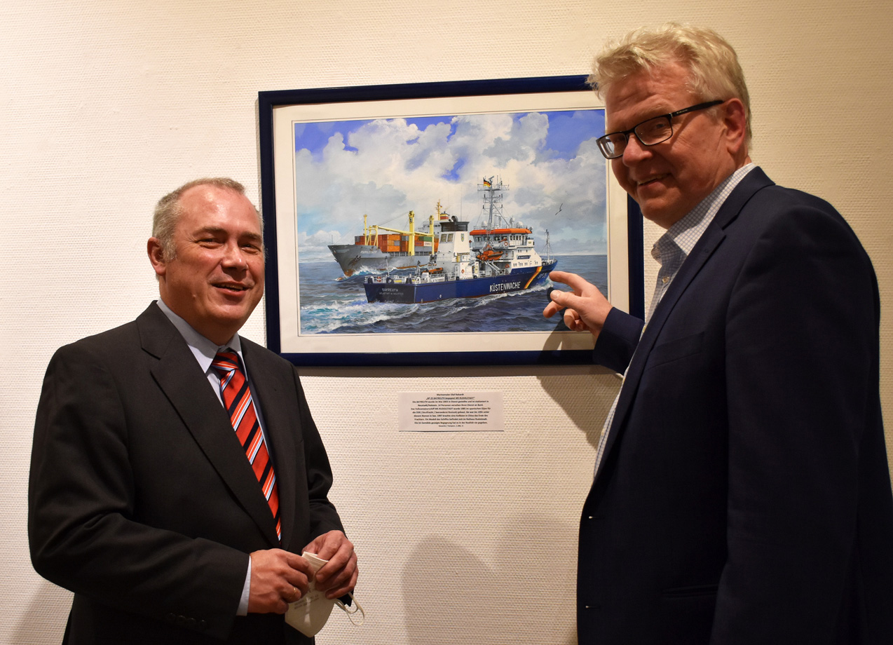 Olaf Rahardt und OB Ebersberger vor einem Bild, das zwei Schiffe zeigt.