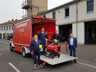 OB Ebersberger, Feuerwehr-Vorstand Bauske und zwei Mitarbeiter stehen vor einem Feuerwehr-Transportfahrzeug.