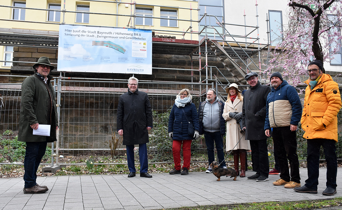 Mehrere Menschen stehen vor der Stadtmauer