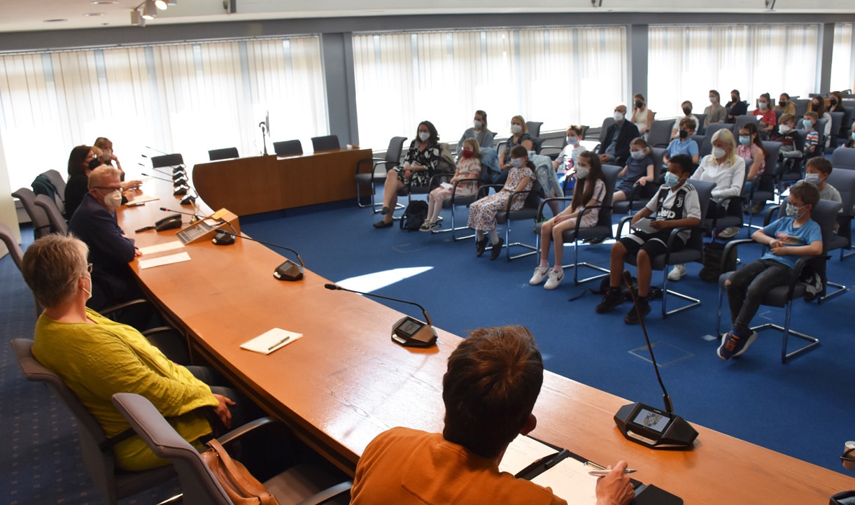 kinderempfang 02 Im Sitzungssaal des Rathauses sitzen zahlreiche Kinder mit Begleitpersonen.