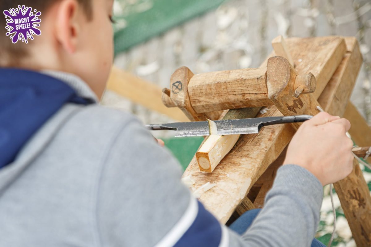 Jugendlicher beim Holz schnitzen