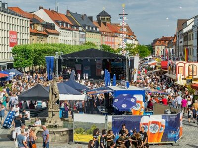 Buntes Treiben auf dem Marktplatz mit Bühne, Bierständen, Bänken