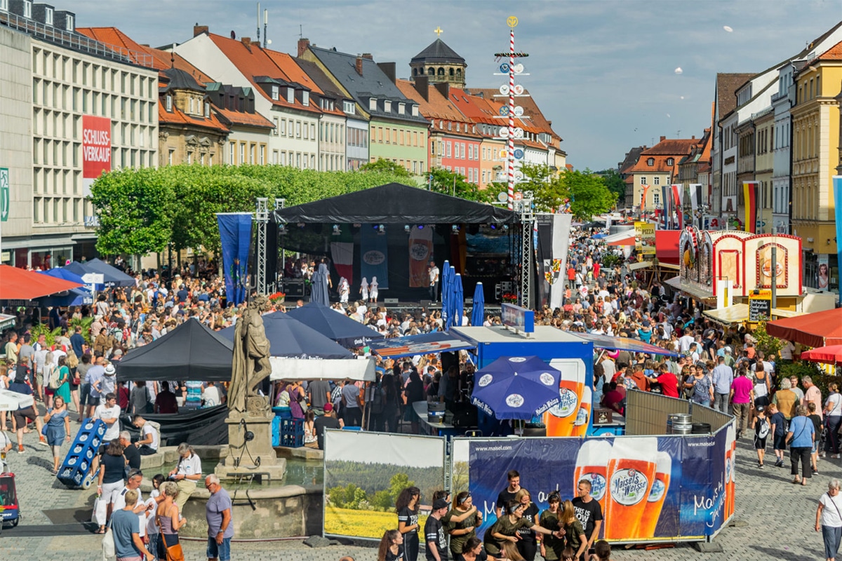 Buntes Treiben auf dem Marktplatz mit Bühne, Bierständen, Bänken