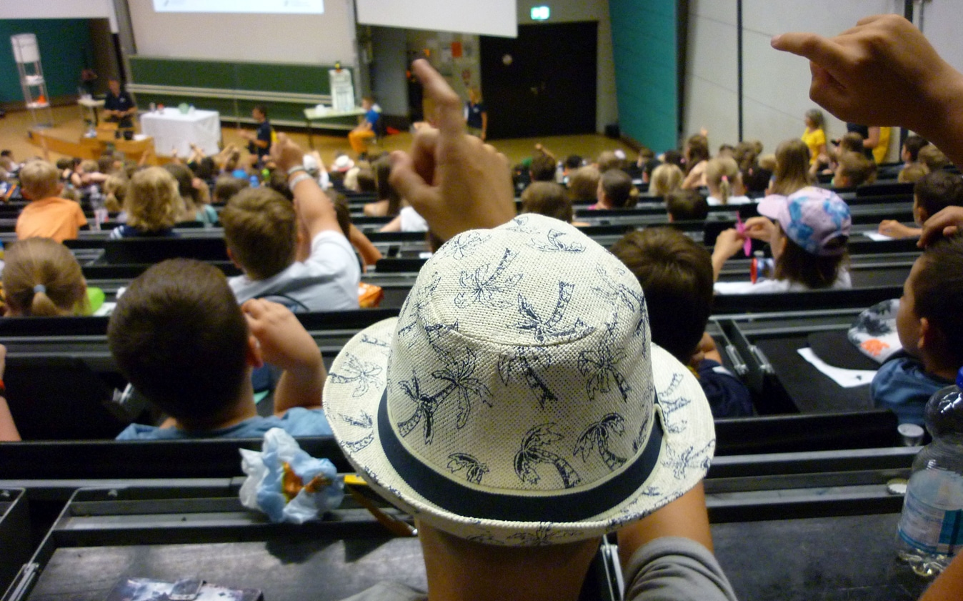 Kinder sitzen in einem Vorlesungssaal der Universität Bayreuth.