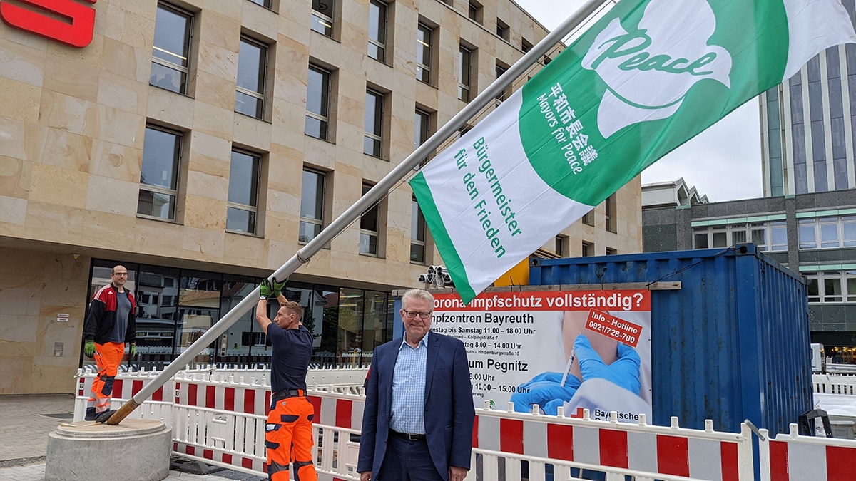 369 Mayors for Peace-6 OB und zwei Mitarbeiter vom Bauhof mit der Fahne in der Hand