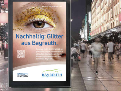 Ein großes Plakat mit Werbung für Bayreuth steht in einer belebten Fußgängerpassage.