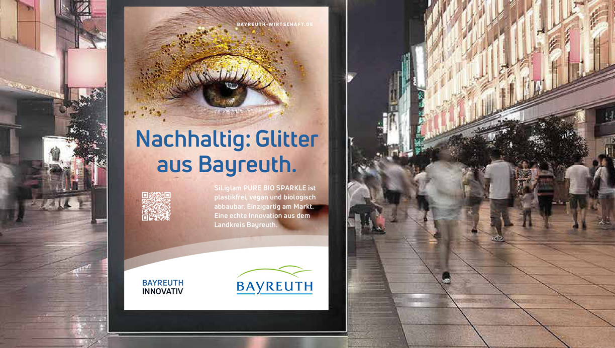 Ein großes Plakat mit Werbung für Bayreuth steht in einer belebten Fußgängerpassage.