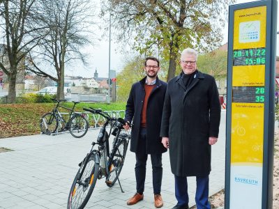OB Ebersberger und Bürgermeister Zippel mit Rad vor der gelben Radzählsäule.