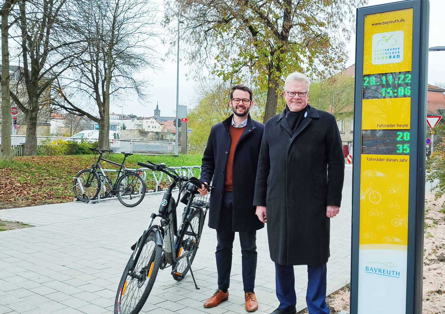 Radzählstelle OB Ebersberge und Bürgermeister Zippel mit Rad an der gelben Radzählsäule.