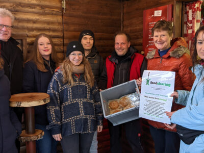 OB Ebersberger, Vertreterinnen der Stadtverwaltung und der Initiative Foodsharing stehen in einer Bude des Christkindlesmarktes.