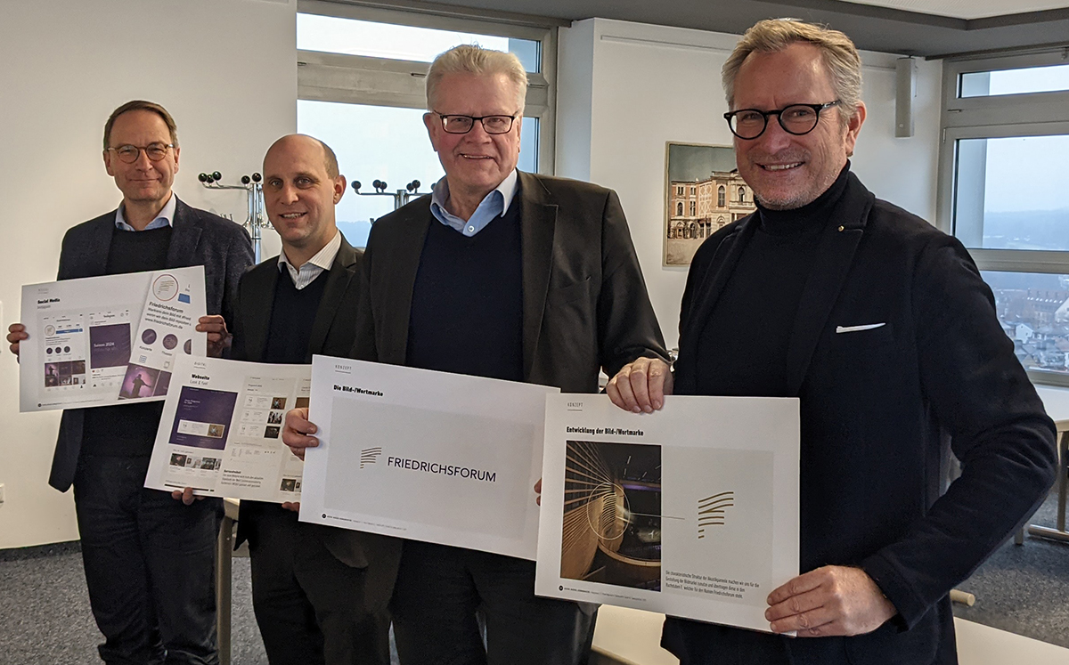 Hendrik Schröder, Benedikt M. Stegmayer, OB Thomas Ebersberger und Jörg Lichtenegger halten Plakate mit dem Logo und anderen Gestaltungselementen in der Hand.