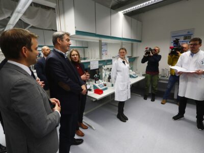 2) Ministerpräsident Dr. Markus Söder (3. v. l.) macht sich vor Ort ein Bild von den Arbeiten am BayBatt, Universitätskanzlerin Dr. Nicole Kaiser (rechts daneben) erläutert Details zum BayBatt.