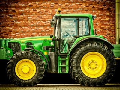 Ein grüner Traktor steht vor einer Häuserwand. | Foto: Pixabay