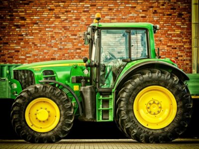 Ein grüner Traktor steht vor einer Häuserwand. | Foto: Pixabay