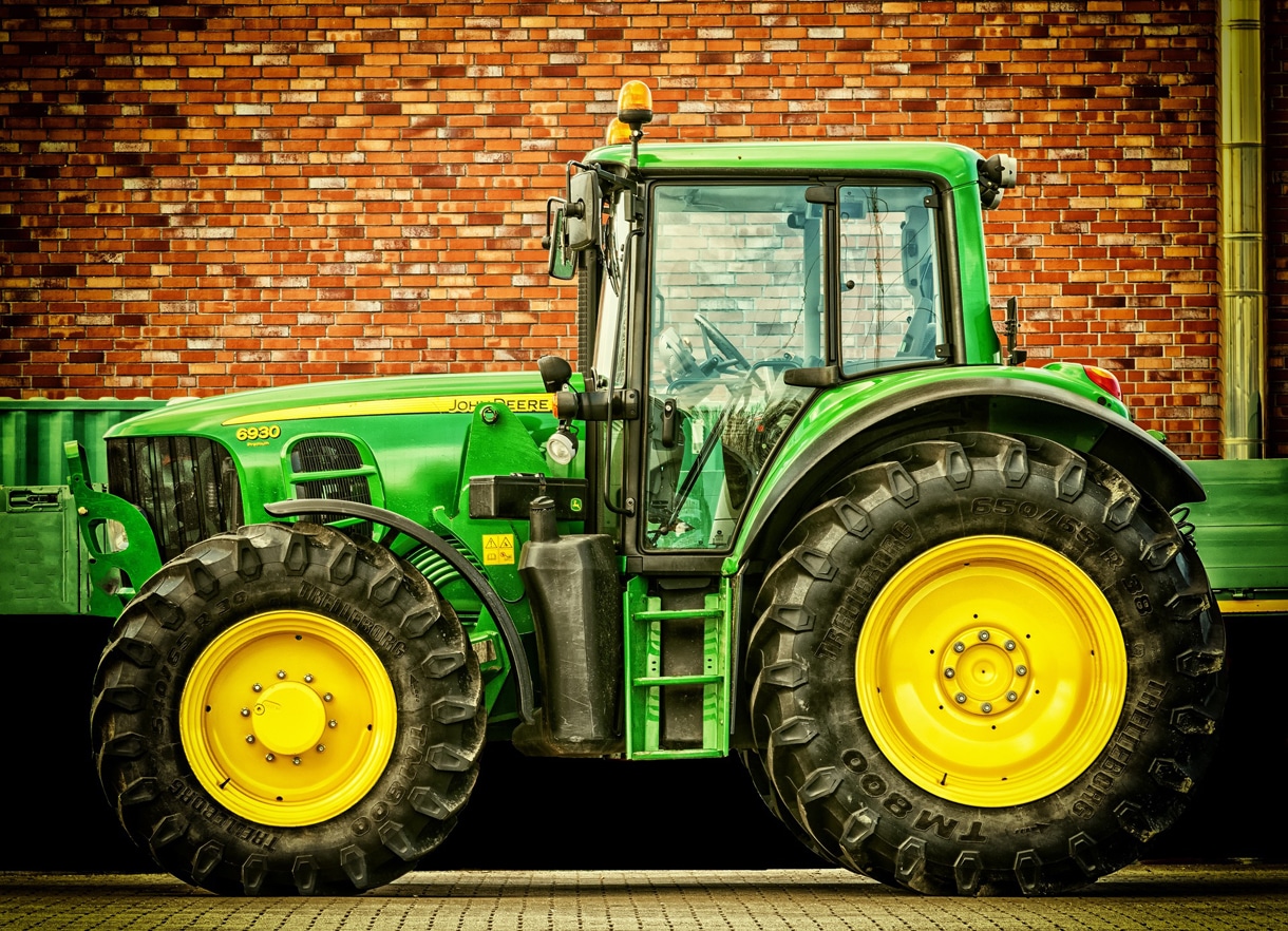 Ein grüner Traktor steht vor einer Häuserwand. | Foto: Pixabay