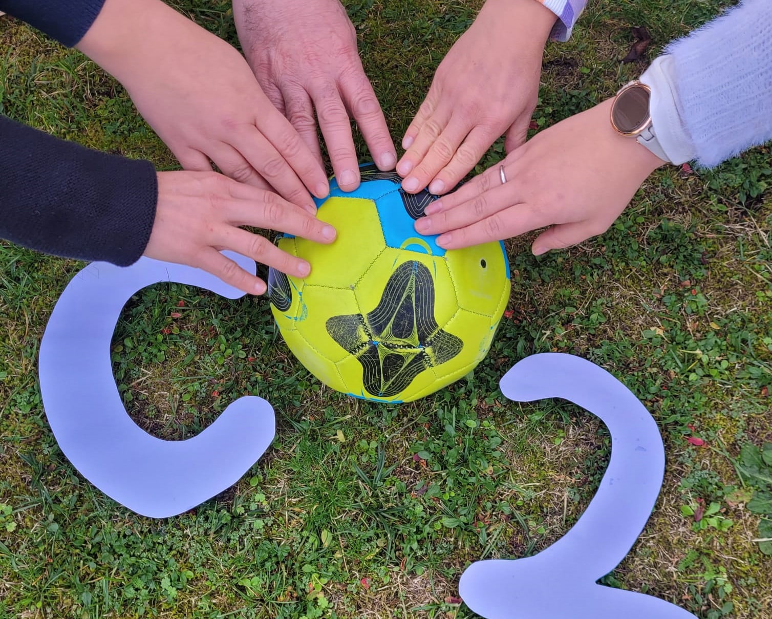 067 CO2_Challenge Vier Hände berühren einen Ball.